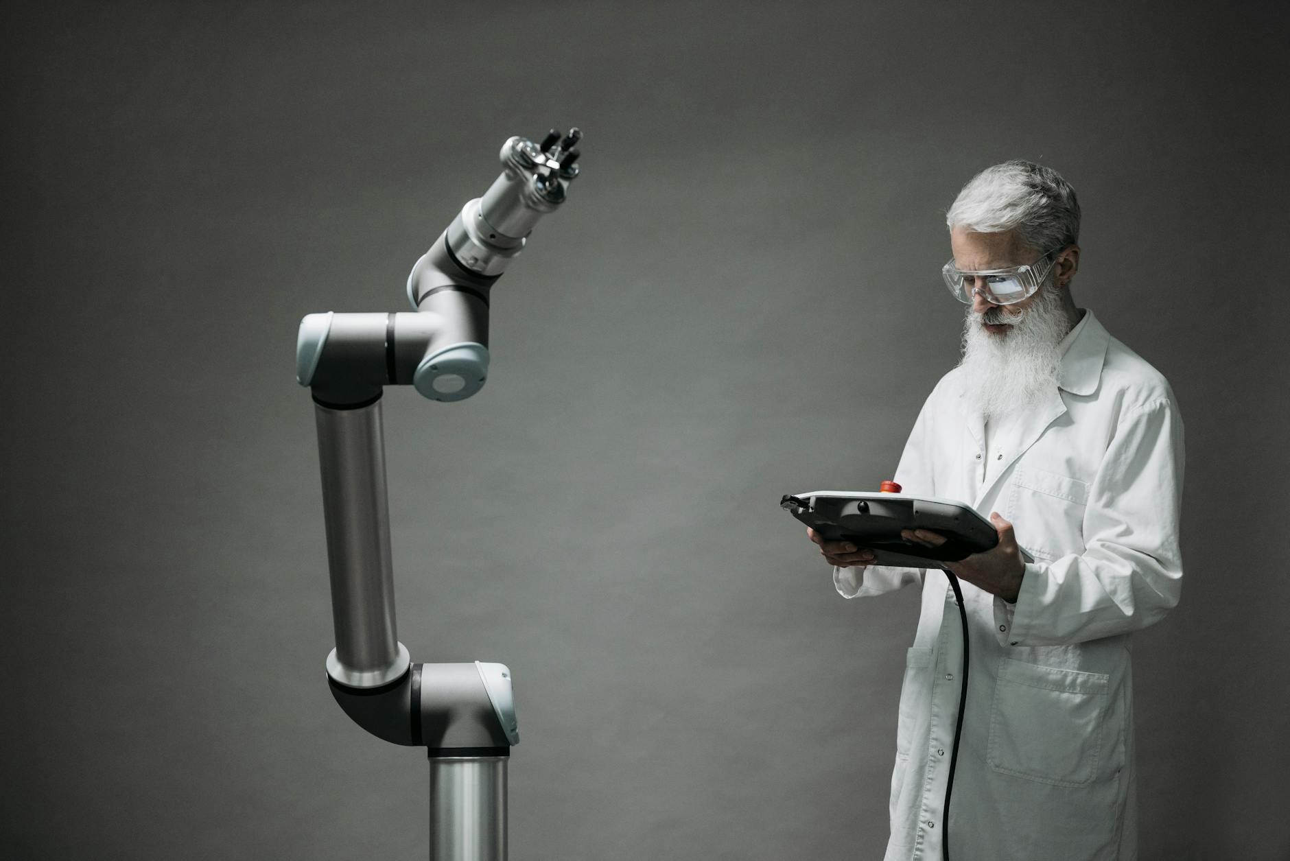 Naukowiec w laboratorium steruje zaawansowanym ramieniem robotycznym